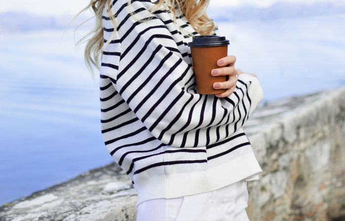 woman wearing a striped sweater holding coffee