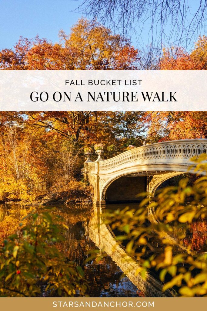 A park with a foot bridge over a pond surrounded with trees with colorful fall foliage, and text that says, "fall bucket list: go on a nature walk."