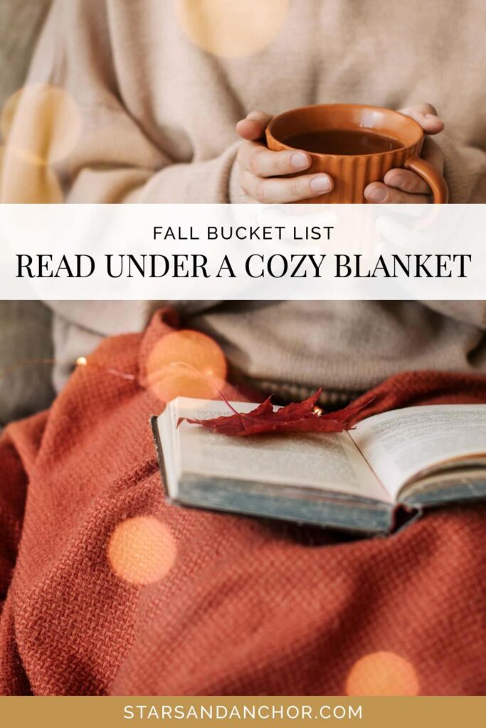 Someone sitting under a blanket with a book on their lap and holding a cup of tea, with text that says, "fall bucket list: read under a cozy blanket."