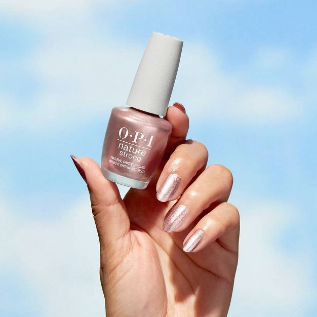 Hand holding a bottle of OPI Intentions Are Rose Gold metallic nail polish.