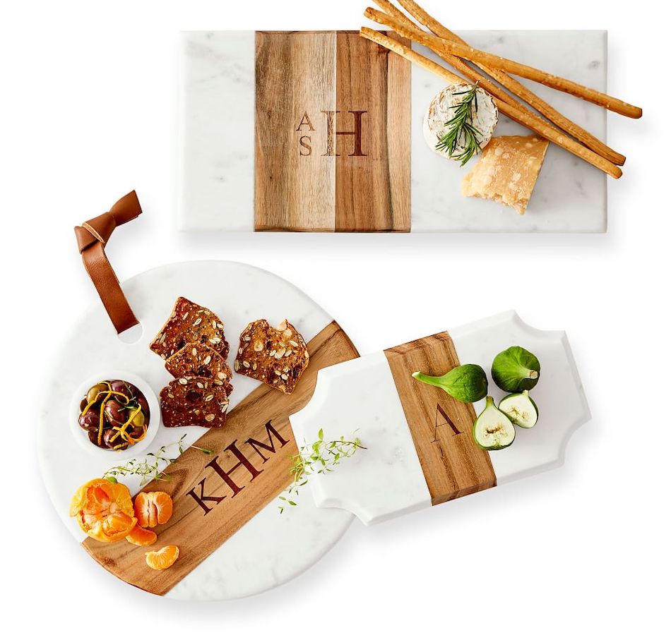Three various shaped wood and marble cheese boards with snacks.