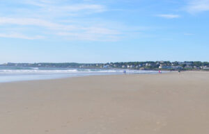 A flat stretch of Ogunquit Beach with people walking in the distance.