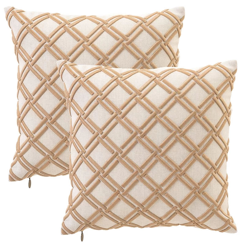 Two geometric embroidered cream and tan coastal throw pillows.