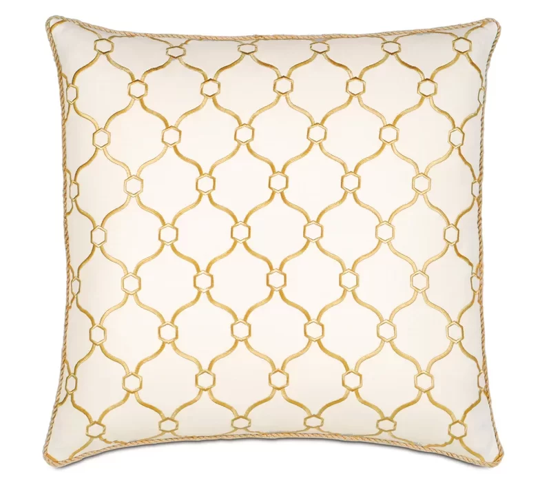 A cream throw pillow with an abstract honey-colored geometric pattern.