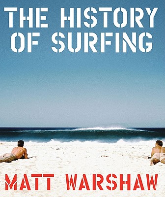 A coffee table book cover that reads, The History of Surfing by Matt Warshaw. There are two men lying on the book looking out towards the ocean at a big wave.