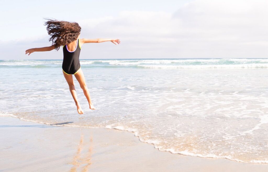 A girl jumping in the waves at the beach.