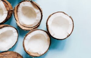 Coconuts that are cut in half on a light blue background.