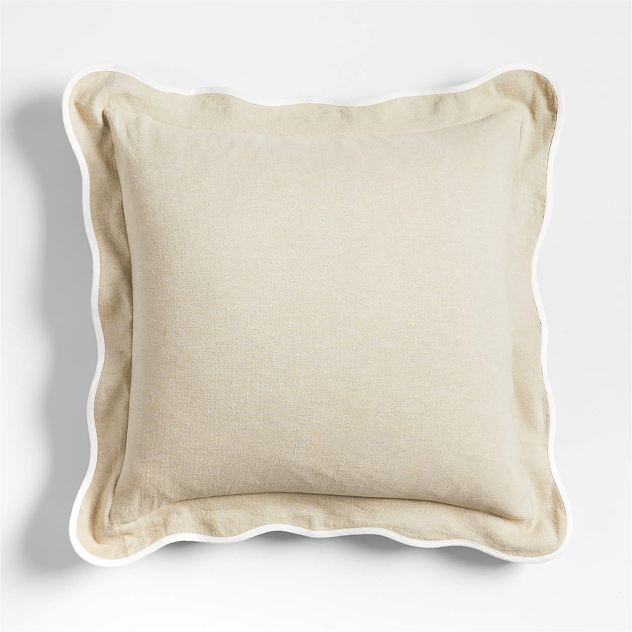 A beige throw pillow with a white scalloped edge.