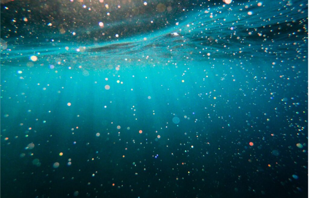 Sunlight streaming through ocean water from below, with colorful light reflections.