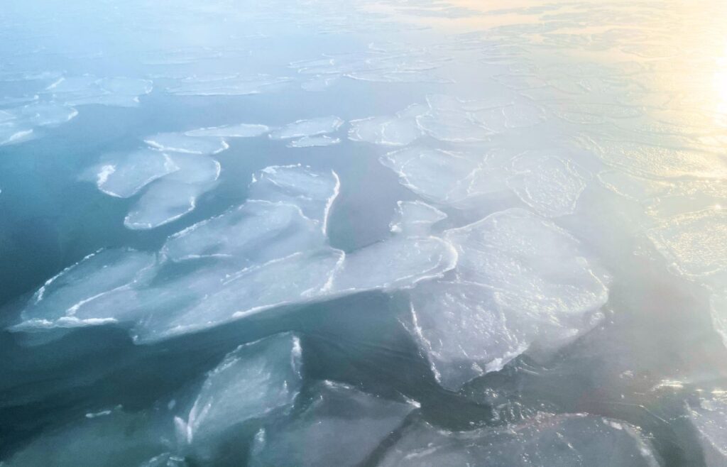 Patches of ice on the water's surface reflecting the sun.