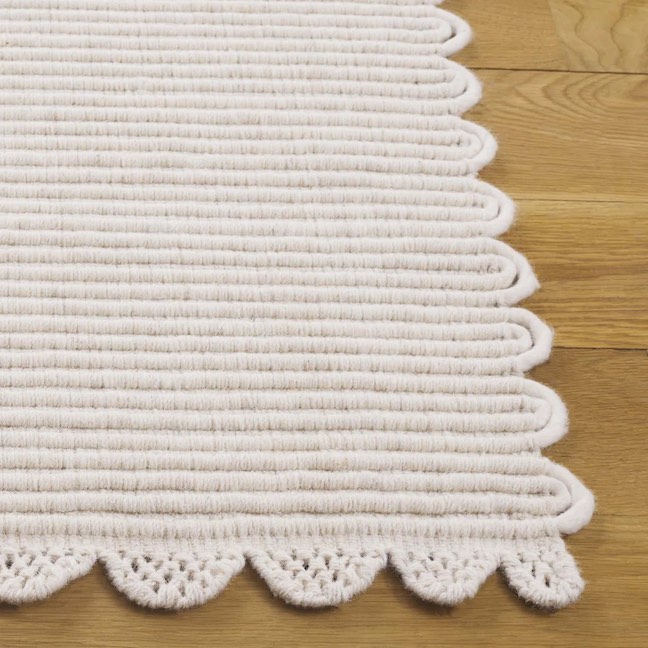 Detail of an ivory scalloped rug with a subtle stripe pattern.