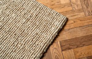 A closeup of a jute rug on a hardwood floor.