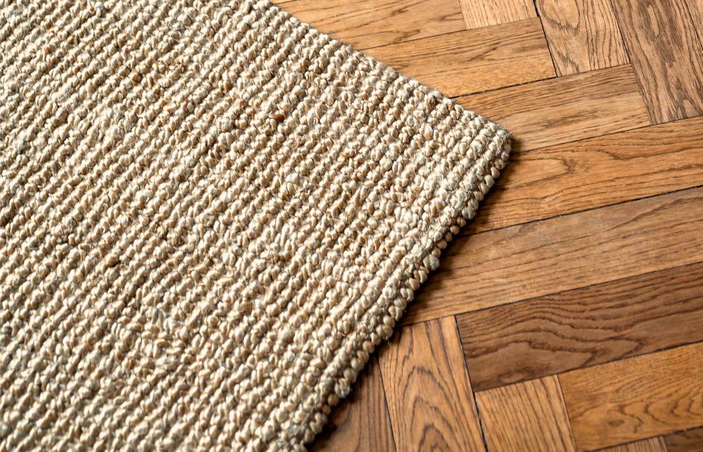 A closeup of a jute rug on a hardwood floor.