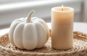 A seagrass tray containing a white ceramic pumpkin and a beige candle.
