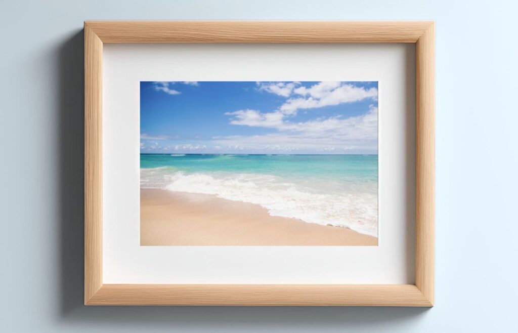 A beach photograph in a light wood frame with a white mat.