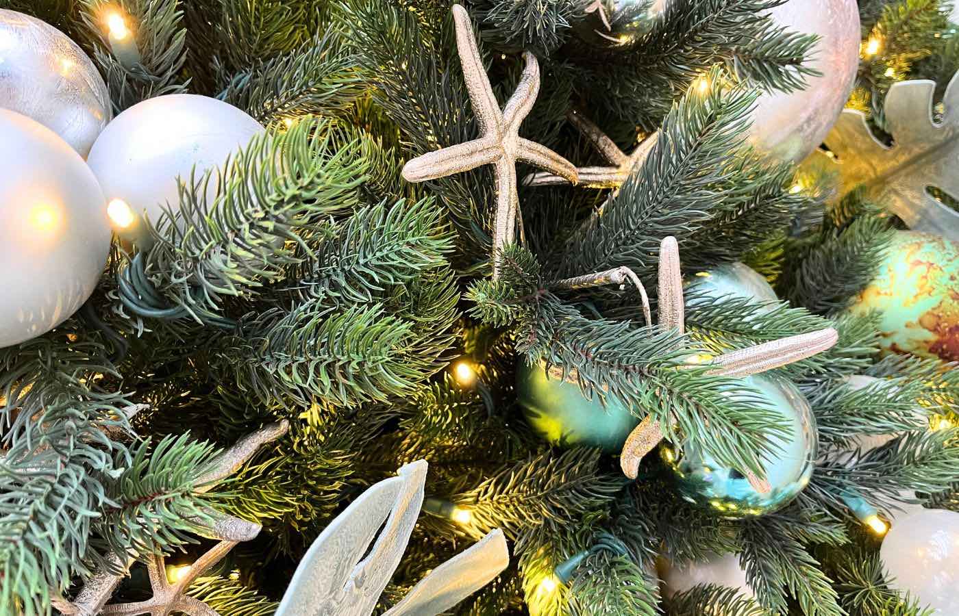 Close up of a Christmas tree decorated in blue and white ornaments and starfish ornaments.