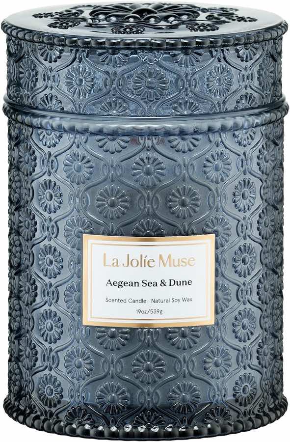 A candle with the scent Aegean Sea & Dune in a navy blue glass container with a lid.