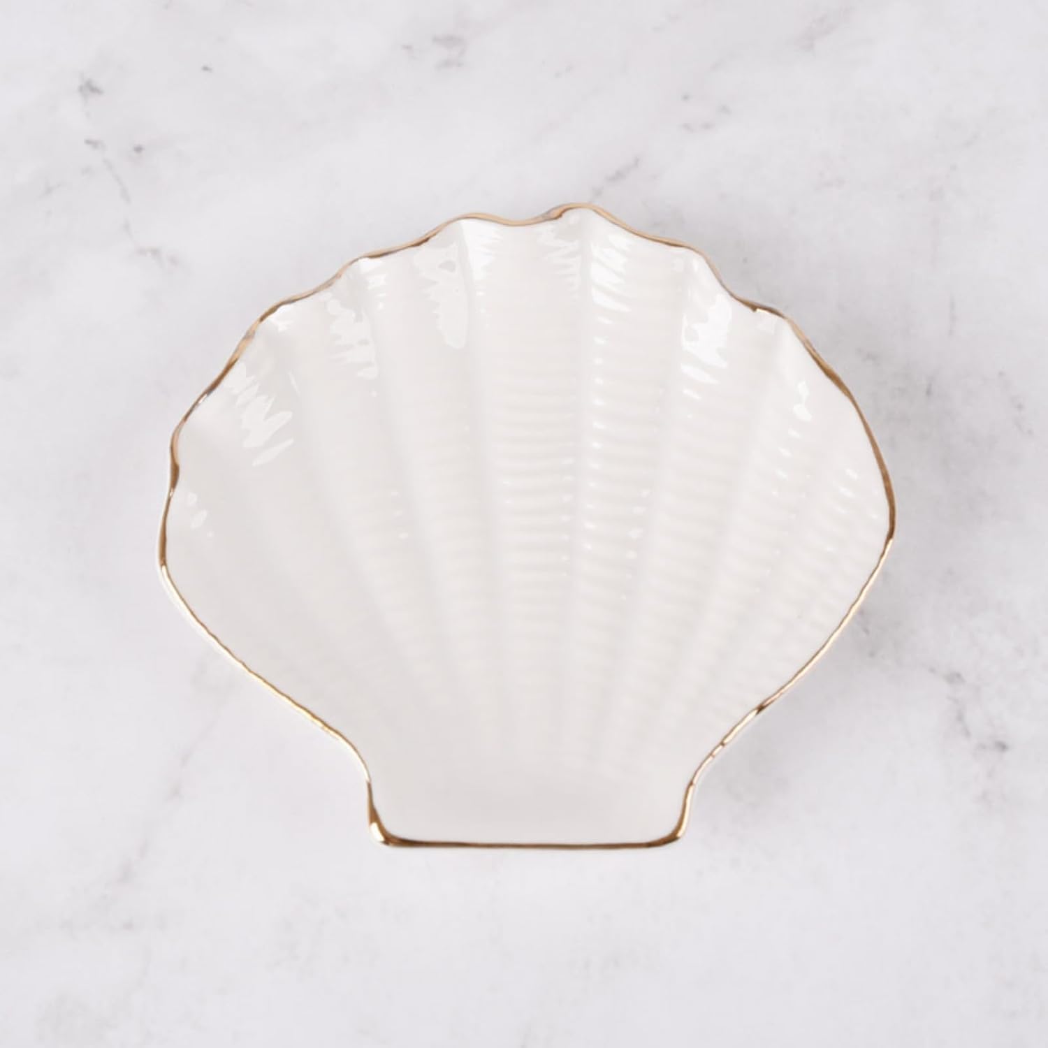 A white and gold seashell jewelry dish.