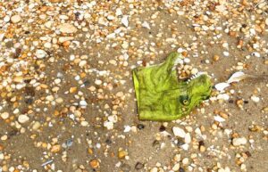 A dinosaur mask on sand and rocks.