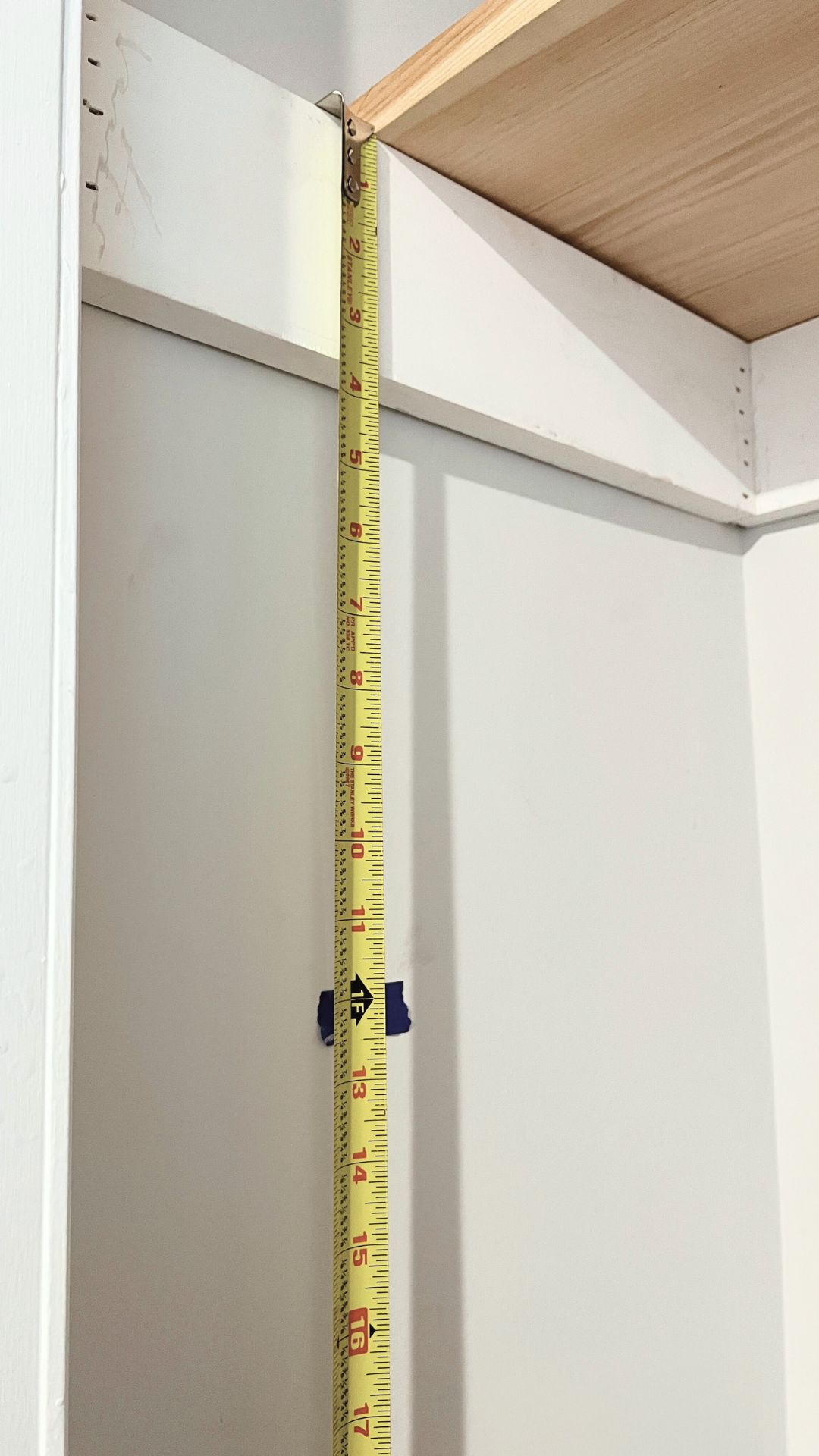 A tape measure being used to mark the location for a new shelf.