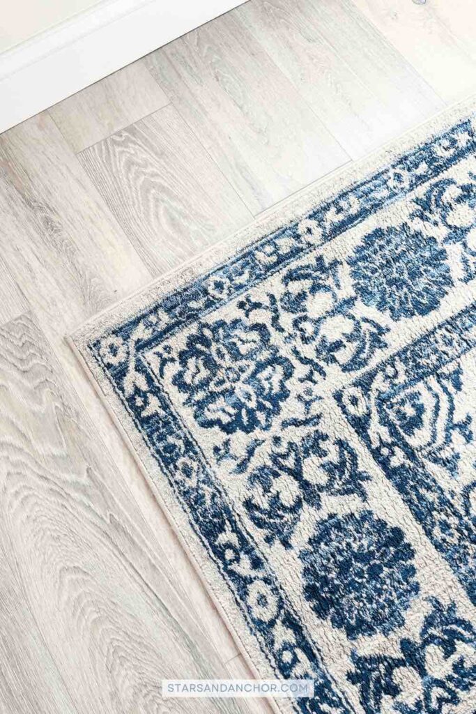 A blue and gray-beige patterned rug on a wood floor.
