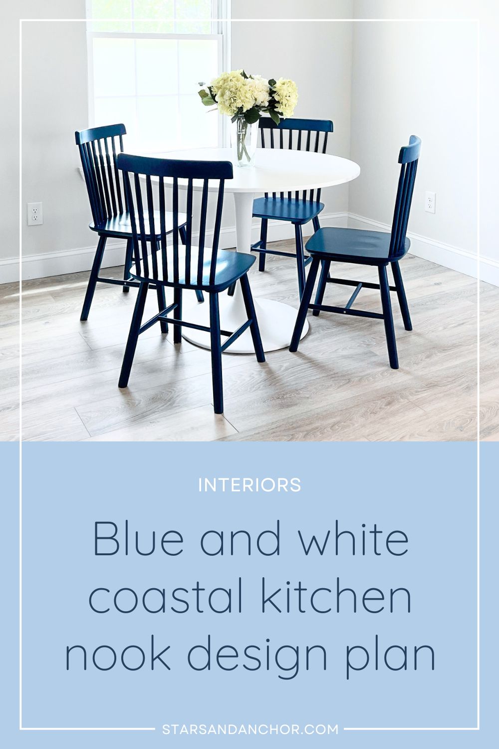 A kitchen dining area with a round white table, navy blue dining chairs, and a vase with flowers. Text on it says, Interiors: Blue and white coastal kitchen nook design plan.