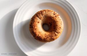 An everything bagel on a white plate.