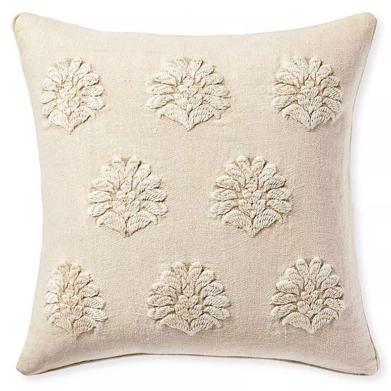 A neutral throw pillow cover with floral embroidery.