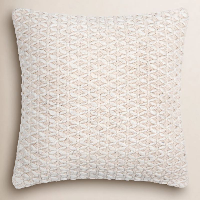A neutral throw pillow with a small textured zigzag pattern.