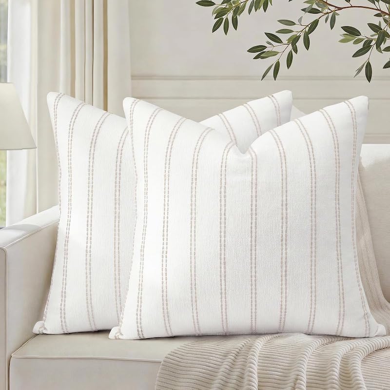 Two white pillows with cream stripes, on a couch.